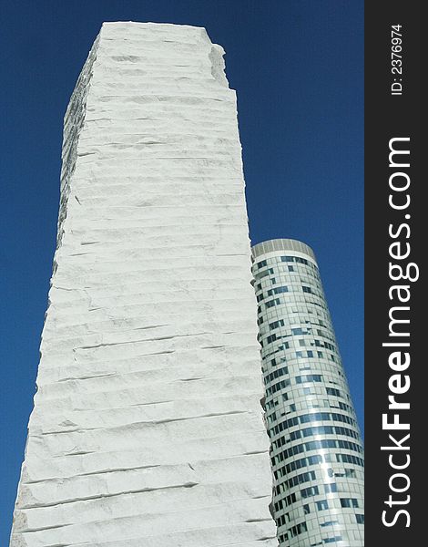 Stone monument in Paris, La Defence , with skyscraper in backgroud