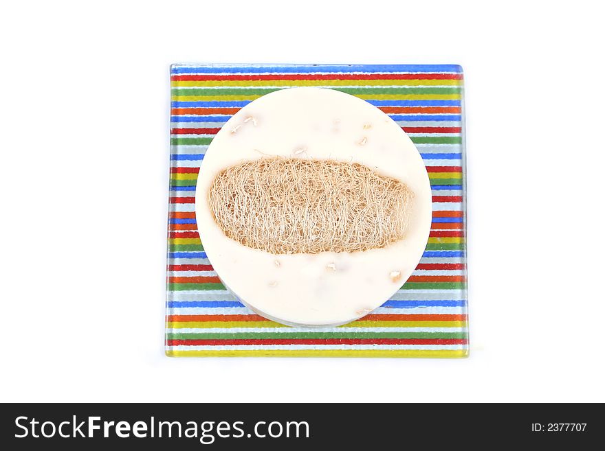 Vanilla soap and loofah on a colorful striped dish - isolated