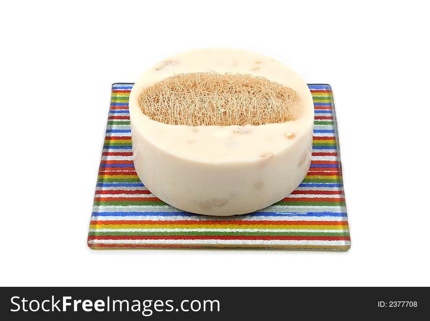 Vanilla soap and loofah on a colorful dish - isolated