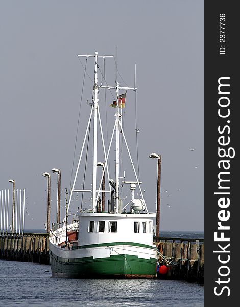 Green fishingboat at quay on blue sky. Green fishingboat at quay on blue sky