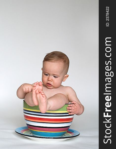 Image of an adorable baby sitting in a colorful, over-sized teacup. Image of an adorable baby sitting in a colorful, over-sized teacup