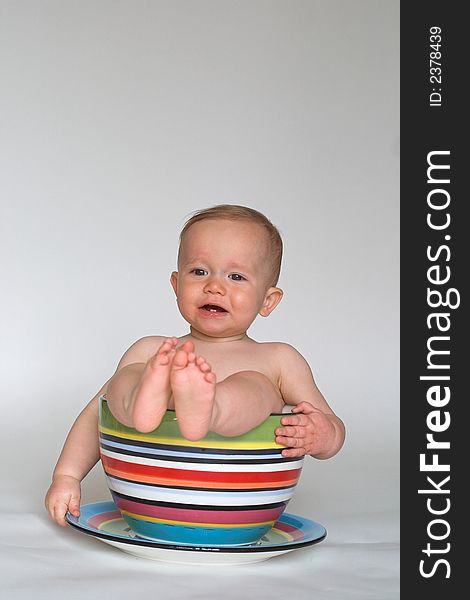 Image of an adorable baby sitting in a colorful, over-sized teacup. Image of an adorable baby sitting in a colorful, over-sized teacup