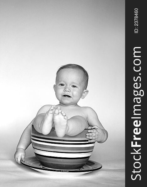 Black and white image of an adorable baby sitting in an over-sized teacup. Black and white image of an adorable baby sitting in an over-sized teacup