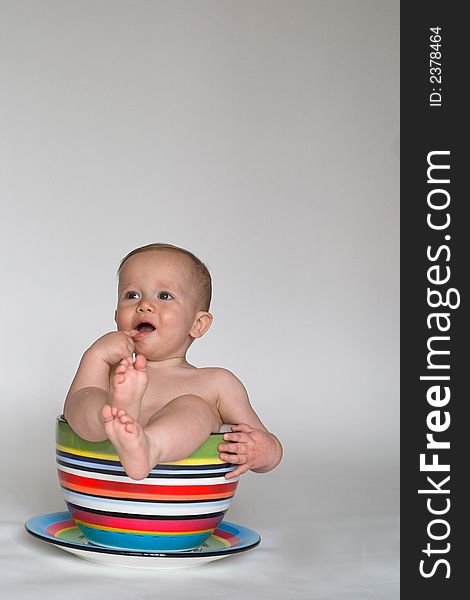 Image of an adorable baby sitting in a colorful, over-sized teacup. Image of an adorable baby sitting in a colorful, over-sized teacup