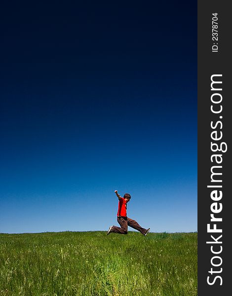 Active happy young man jumping in a green field against a clear blue sky. Active happy young man jumping in a green field against a clear blue sky