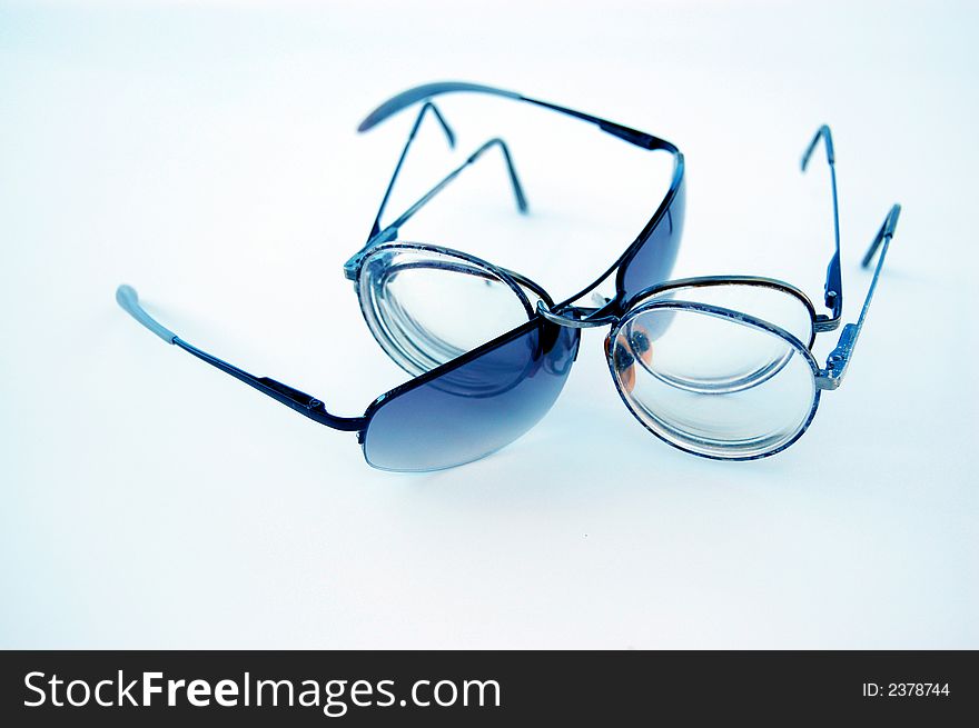 Three pair of eyeglasses, posed on a white, blue filtered background in a dynamic tension. Three pair of eyeglasses, posed on a white, blue filtered background in a dynamic tension.