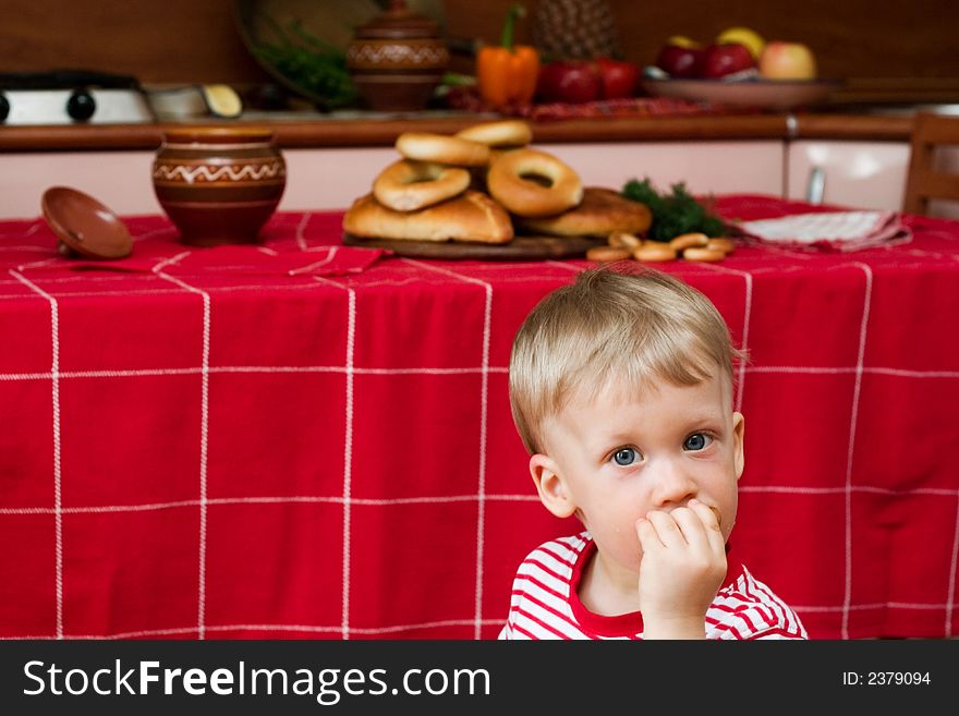 Little boy eating cracknel in the kitchen