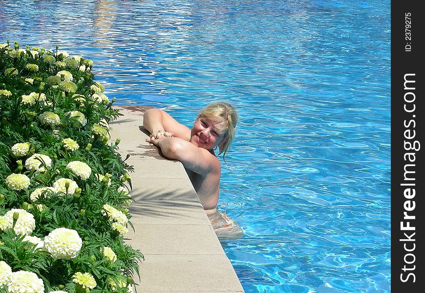 Young, smiling woman relaxing in the sunny pool at resort. Young, smiling woman relaxing in the sunny pool at resort