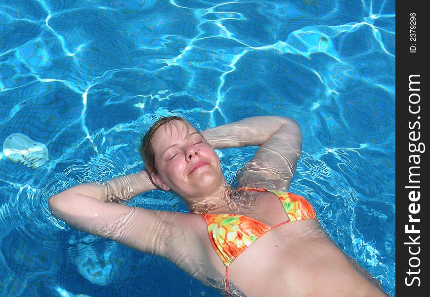 Young, smiling woman relaxing in the sunny pool at resort. Young, smiling woman relaxing in the sunny pool at resort