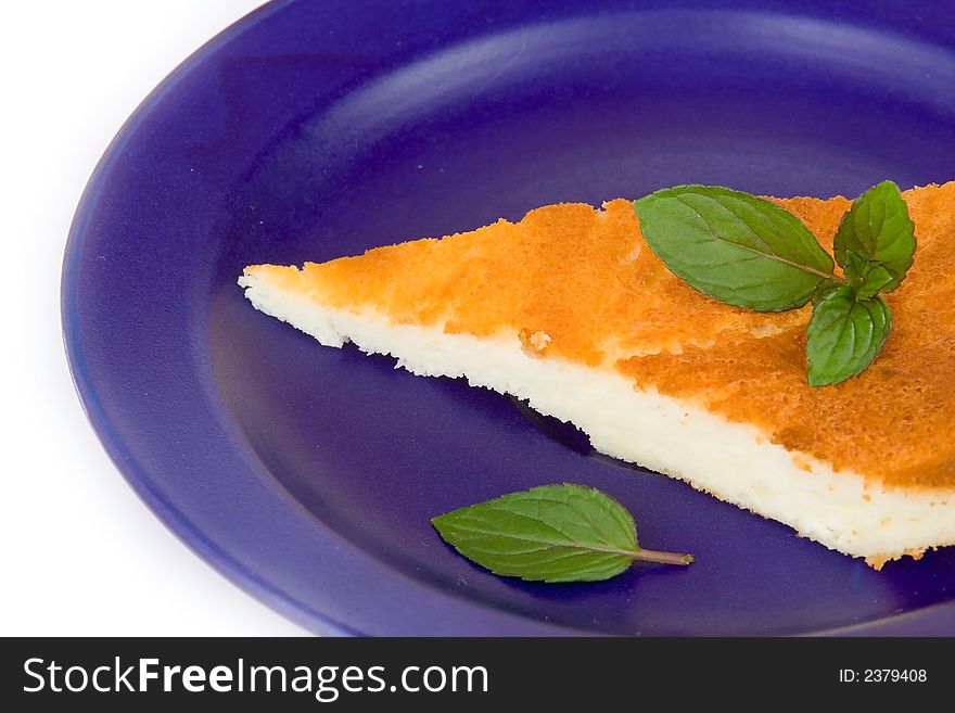 Cake slice on blue plate with mint leaves