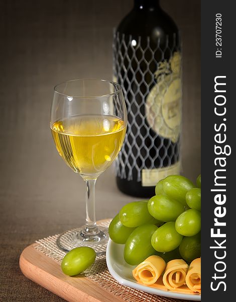 A Glass Of White Wine, Green Grapes And A Bottle O