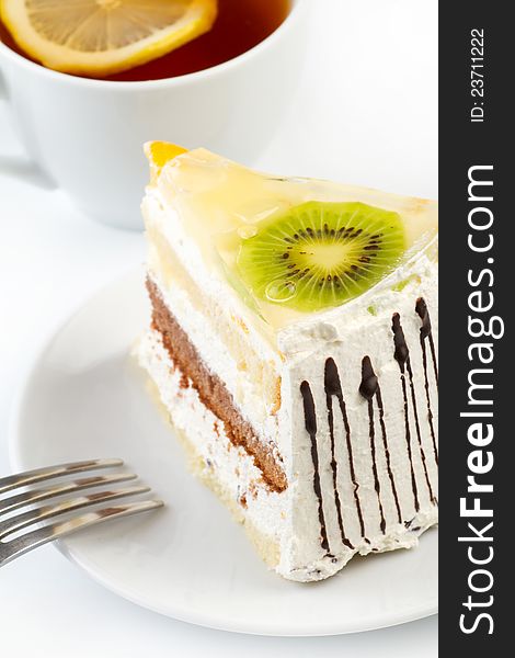 A cup of tea and a piece of tasty creamy cake with fruits