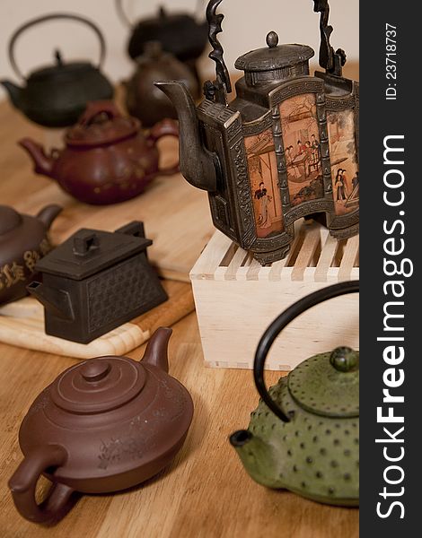 A collection of Japanese and Chinese teapots on a wooden table. A collection of Japanese and Chinese teapots on a wooden table
