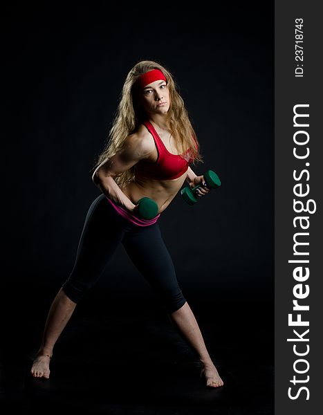 Fitness girl with dumbbell on black