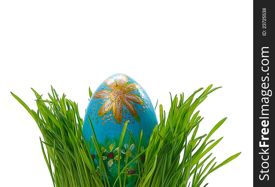 Ornated blue easter egg between green grass isolated on white background. Ornated blue easter egg between green grass isolated on white background
