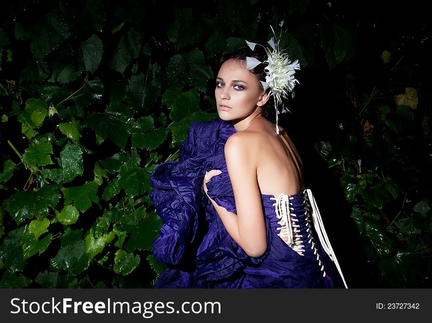 Nocturnal scenery - fashionable woman in blue dress among green plants. Nocturnal scenery - fashionable woman in blue dress among green plants