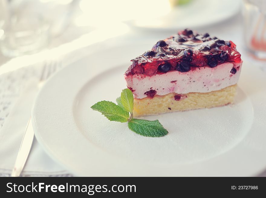 On a white plate an appetizing cake with a mint leaf. On a white plate an appetizing cake with a mint leaf