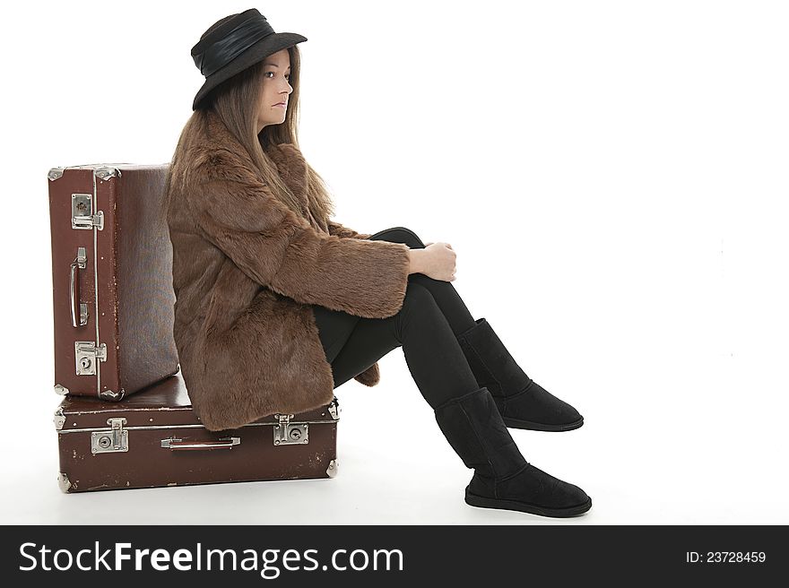 Young woman is sitting on the luggage, studio shot. Young woman is sitting on the luggage, studio shot