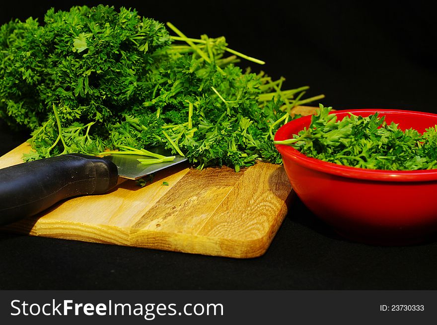 Chopped parsley with a knife and a red bowl. Chopped parsley with a knife and a red bowl
