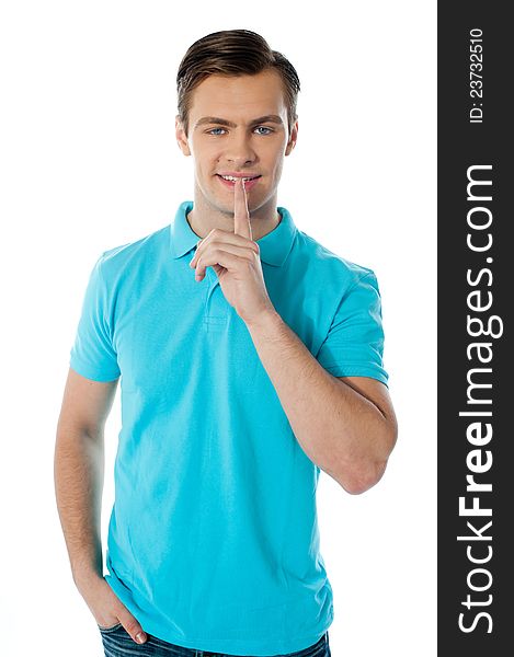 Silence gesture by a young guy wearing blue t-shirt against white background. Silence gesture by a young guy wearing blue t-shirt against white background