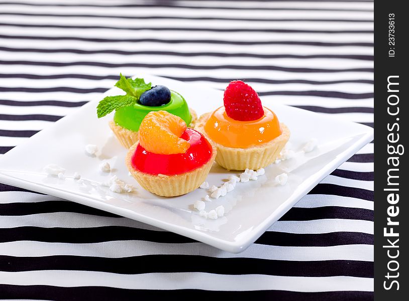Sweet snack jelly raspberry blueberry and orange cupcake display on dish. Sweet snack jelly raspberry blueberry and orange cupcake display on dish