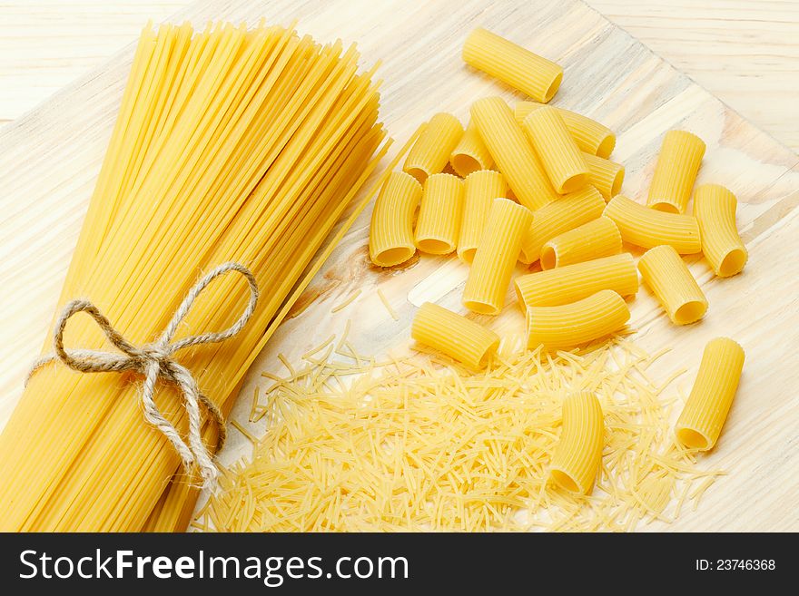Different types of raw pasta, noodle, spaghetti, tortiglioni on wooden table. Different types of raw pasta, noodle, spaghetti, tortiglioni on wooden table