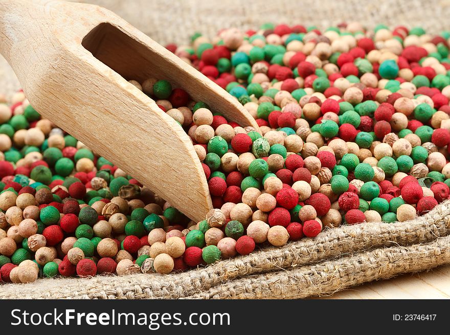Colorful peppercorns mix, wooden scoop on sack