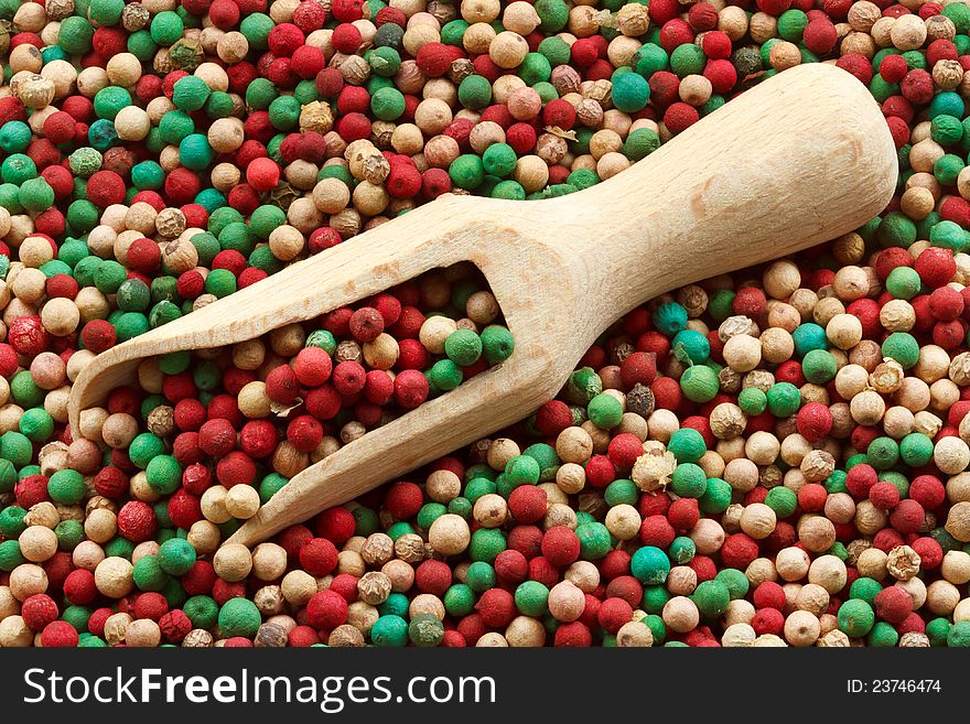 Wooden scoop and background of black, white, green and pink Peppercorns. Wooden scoop and background of black, white, green and pink Peppercorns