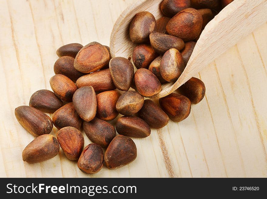 Wooden scoop with pine nuts on table