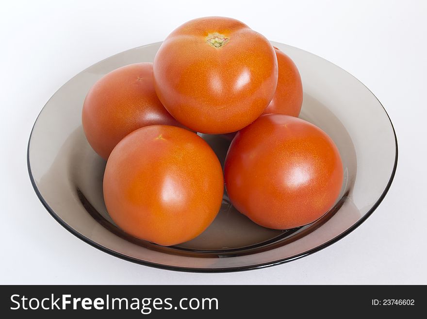 Pyramid of tomatoes in black plate on white background