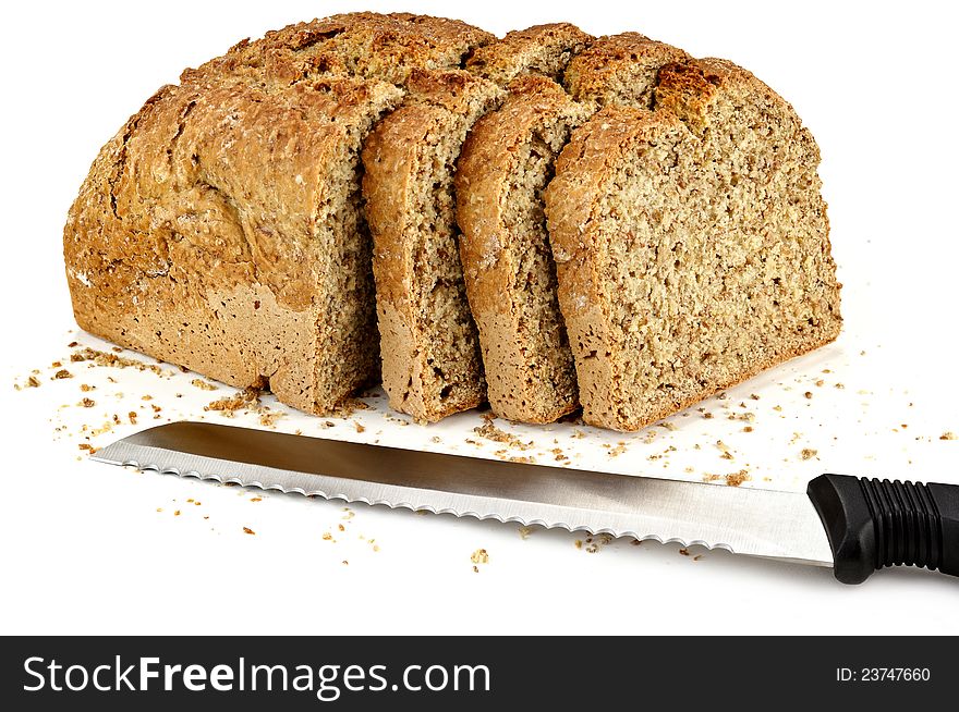 A loaf of bread with a three slices and a knife on a white table
