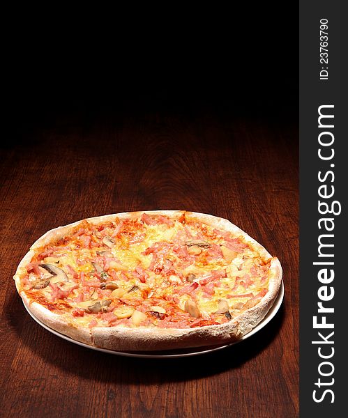 Pizza on a wooden table and black background