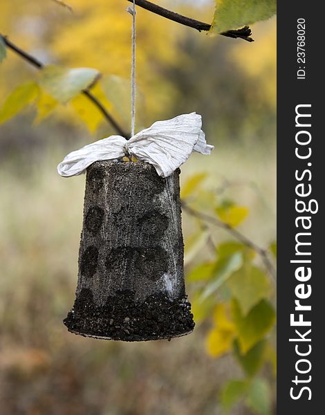 Stone bell with a paper ribbon, a bell hung on a branch, bell isolated from the background, yellow leaves in the background of the bell, handmade decorations