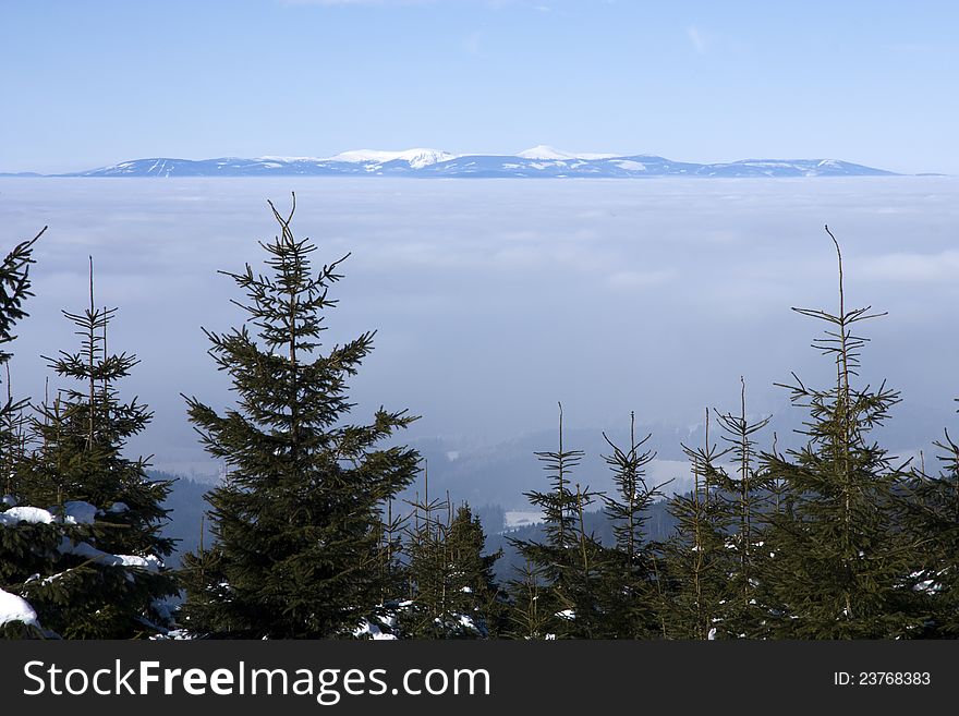 Winter mountain landscape of the Eagle Mountains, a view of the valley with mist, the mountains of the Czech Republic, sunny day in the mountains, the mountains with blue sky