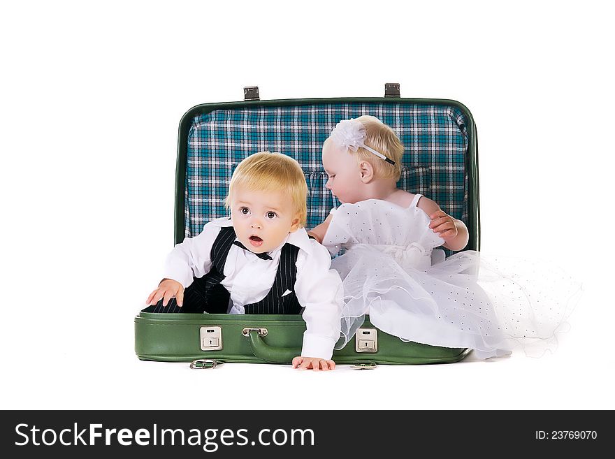 Boy and a girl dressed as newlyweds sitting in a suitcase, going to travel. Boy and a girl dressed as newlyweds sitting in a suitcase, going to travel