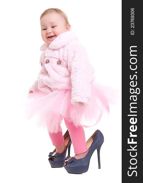 Happy baby in the shoes of adults, and a pink tutu on the white backgraund