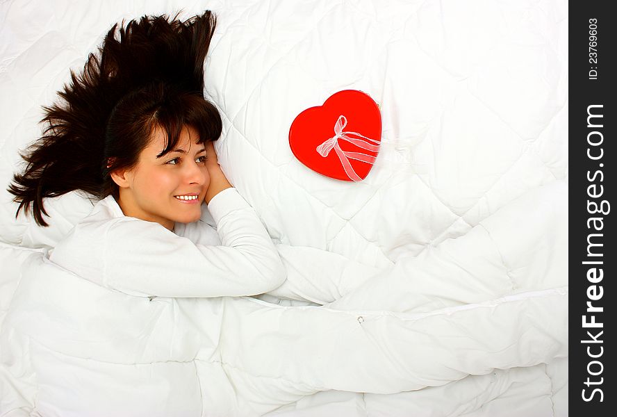 Beautiful woman in bed finding a red gift with heart shape. Beautiful woman in bed finding a red gift with heart shape