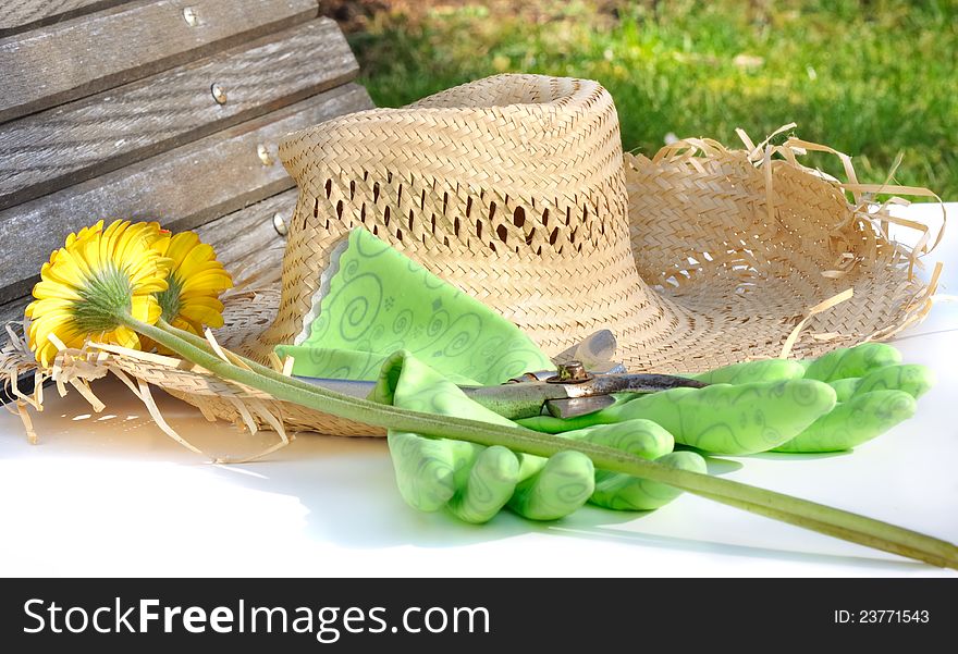 Straw hat next to gloves and pruners and cut flowers in a garden. Straw hat next to gloves and pruners and cut flowers in a garden