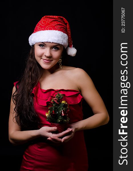 New year girl in red dress with small new year tree isolated on black