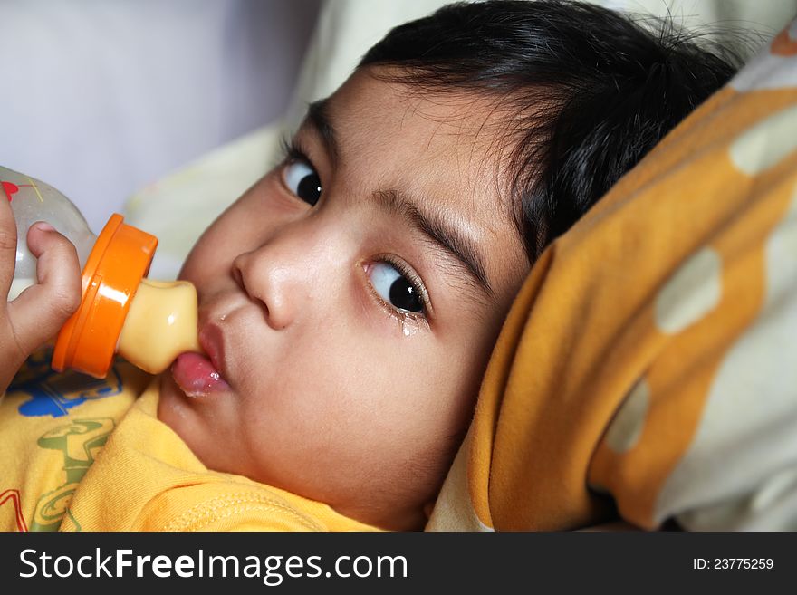 A crying young boy drinking milk from a bottle. A crying young boy drinking milk from a bottle