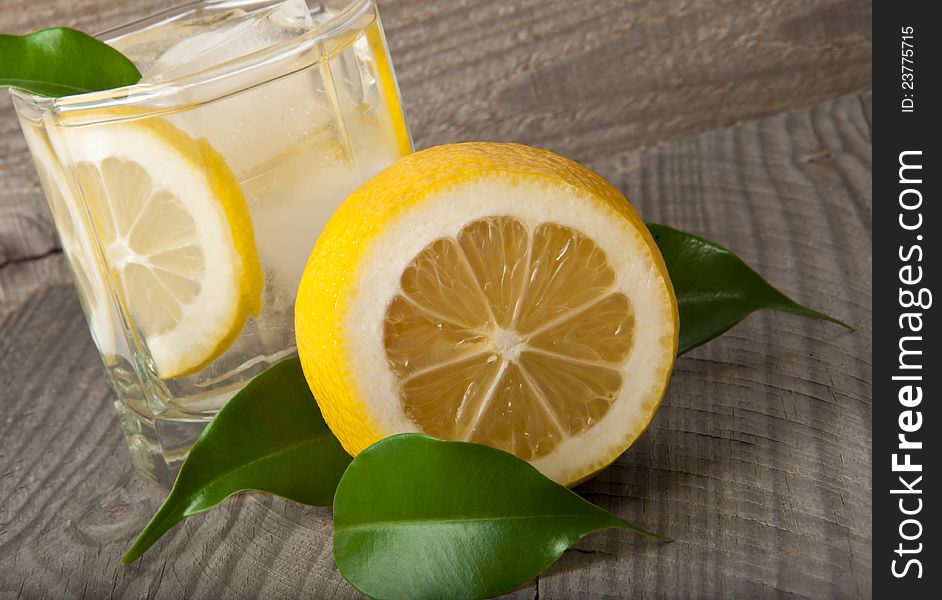 Cocktail glass with lemon and ice on wooden background