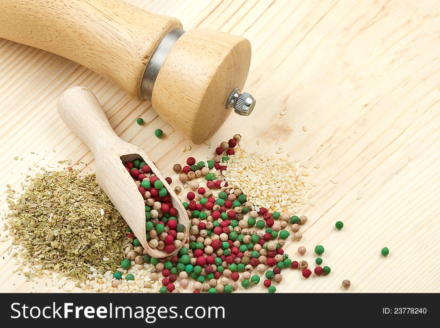 Spice on wooden table: pepper mill, wooden scoop, peppercorn, sesame seeds, dried herbs, top view. Spice on wooden table: pepper mill, wooden scoop, peppercorn, sesame seeds, dried herbs, top view