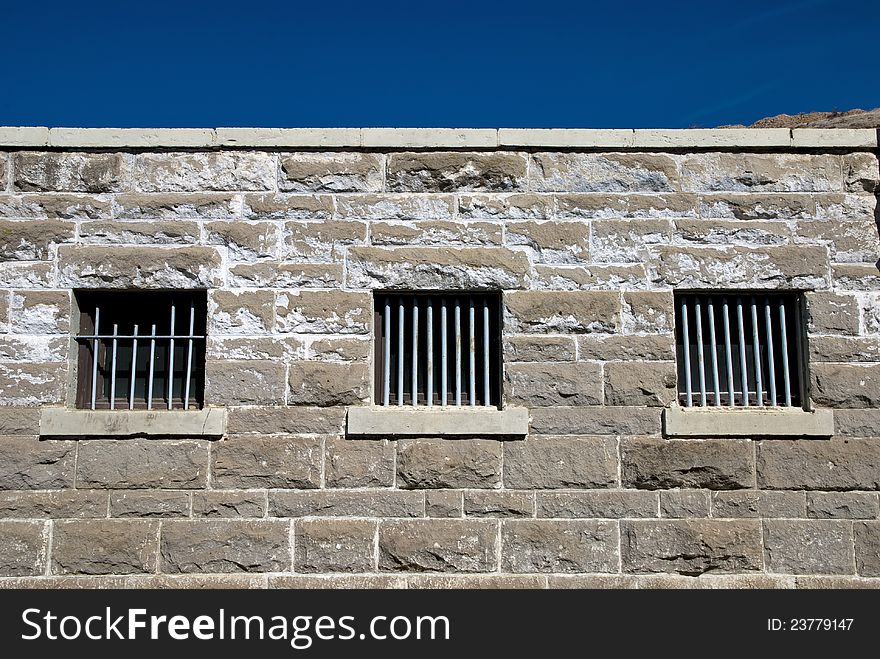 Sandstone wall with the barred windows of a prison. Sandstone wall with the barred windows of a prison