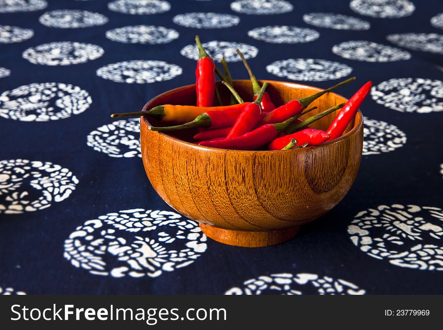 A wooden bowl with red and yellow peppers in it. A wooden bowl with red and yellow peppers in it.