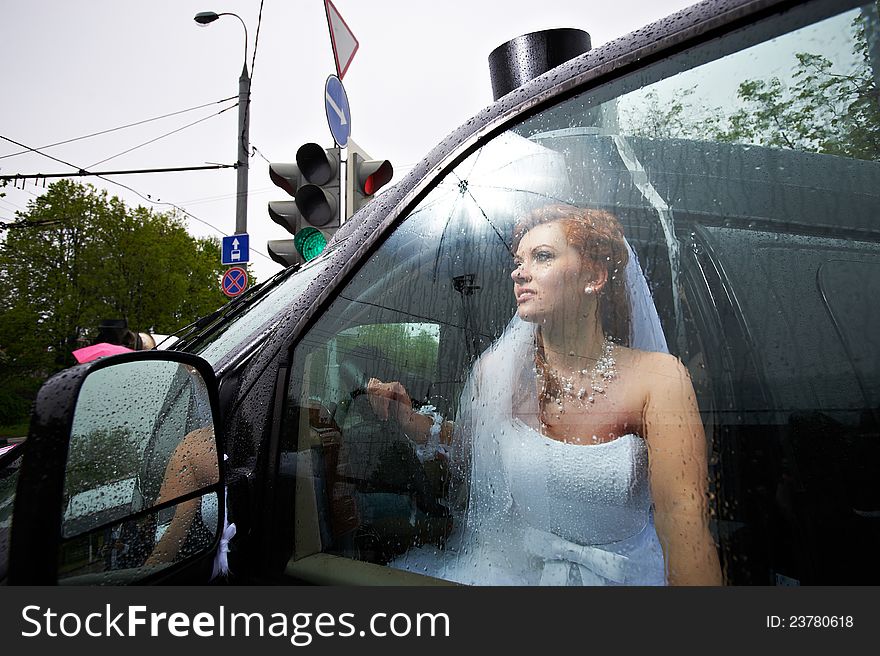 Elegant bride into big car in rainy day