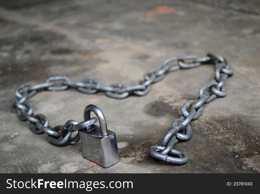 Chain & padlock made into heart shape on a dirty floor. Chain & padlock made into heart shape on a dirty floor