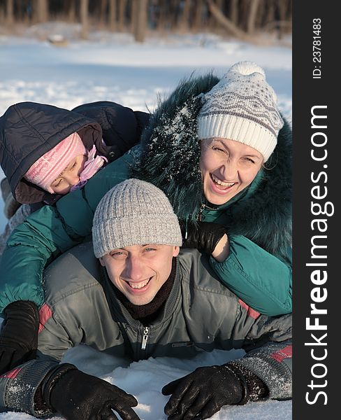 Happy family lying on the snow in the winter