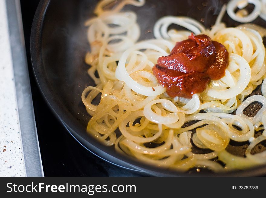 Onions rings with tomato sauce with skillet closeup. Onions rings with tomato sauce with skillet closeup