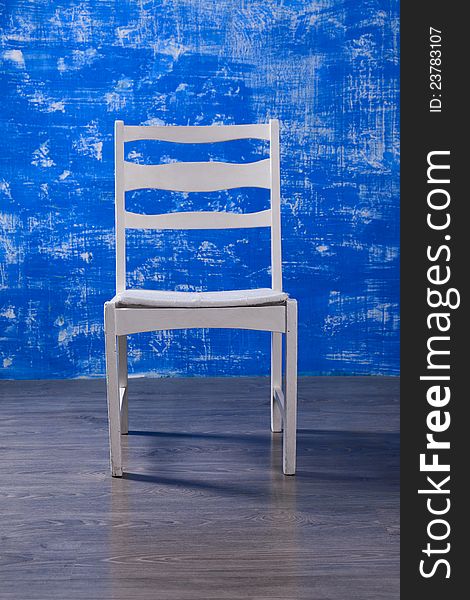 White chair against a background of blue and white wall in an oak floor