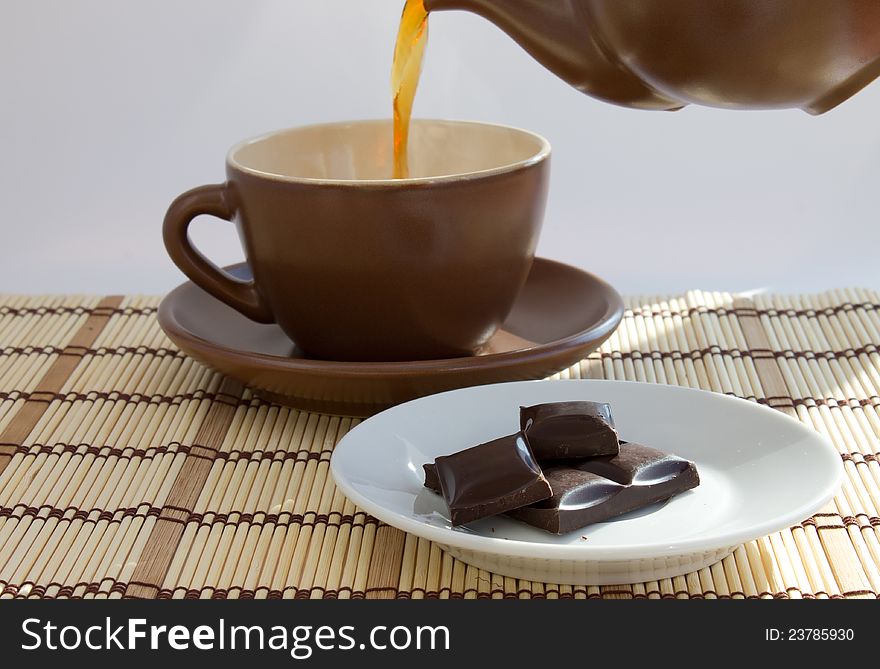 Ceramic teacup with teapot and dark chocolate. Ceramic teacup with teapot and dark chocolate